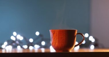 Kahveli tahta bardak. Buhar sıcak kahve, çikolata ve çaydan geliyor. Arka planda Noel ışıkları var. Noel yaklaşıyor.