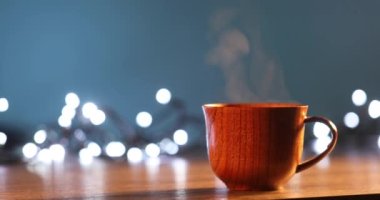 Kahveli tahta bardak. Buhar sıcak kahve, çikolata ve çaydan geliyor. Arka planda Noel ışıkları var. Noel yaklaşıyor.