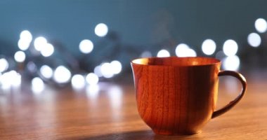 Kahveli tahta bardak. Buhar sıcak kahve, çikolata ve çaydan geliyor. Arka planda Noel ışıkları var. Noel yaklaşıyor.