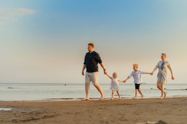 Kafkasyalı güzel bir aile gün batımında denizde koşuyor. Çocuklarla yaz tatili. Yüksek kalite fotoğraf