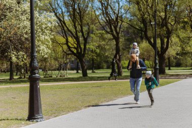 İki oğluyla birlikte sokakta koşan bir baba. Sonbahar zamanı çocuklarla temiz havada vakit geçirmek. Saint-Petersburg, Rusya