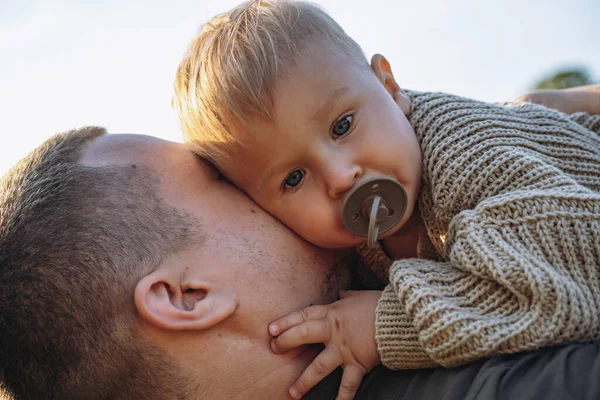 Küçük bebek babasının ellerinde, emzik emiyor. Birlikte dışarıda vakit geçirmek. Babalar Günü. Yüksek kalite fotoğraf