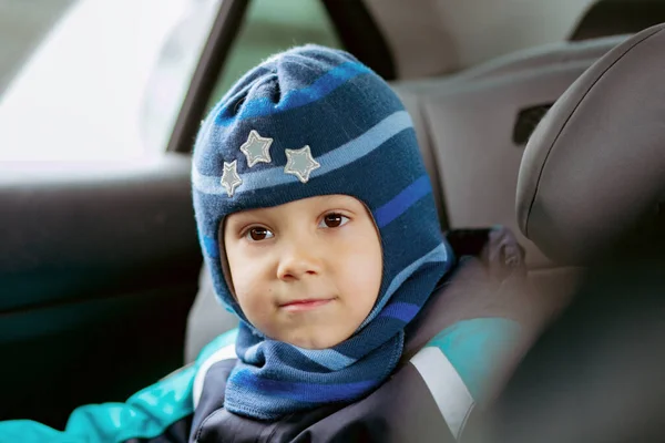 冬の服装をした車の中のチャイルドシートに座ってる可愛い男の子と帽子 選択的焦点で画像 高品質の写真 — ストック写真