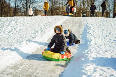 Parktaki buzlu yamaçtan kayan beyaz çocuklar. Kış aktiviteleri konsepti. Mutlu bir çocukluk. Seçici odaklı görüntü. Yüksek kalite fotoğraf