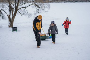 Adam ve beyaz çocuklar. İnsanlar kış parkında kar borularına bindikten sonra yamaca tırmanıyorlar. Seçici odaklı resim