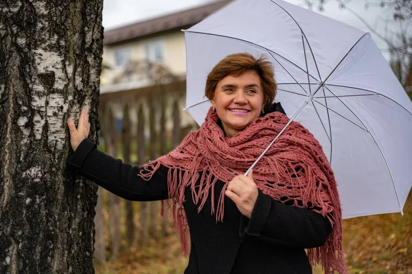 Bir kadın elinde şemsiyeyle sonbahar yürüyüşüne çıkmış.