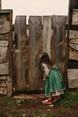 Güzel yeşil elbiseli şirin çocuklar çiftlikte keçi arka planında yürüyorlar.