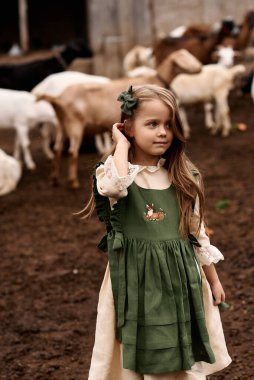 Çiftlikte yürüyen yeşil elbiseli şirin bir çocuğun portresi. 