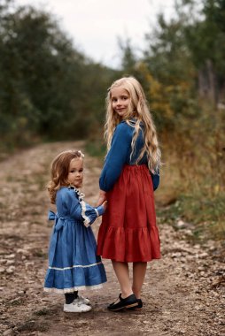 Güzel elbiseli şirin çocuklar çiftlikte keçi arka planında yürüyorlar.