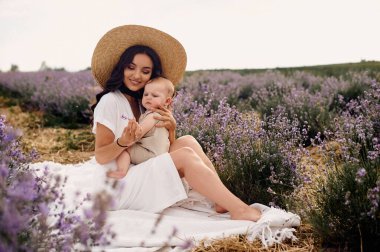 çekici genç anne bebeğiyle lavanta tarlasında oynuyor.