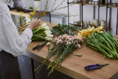Güzel, genç bir çiçekçi buket yapıyor.