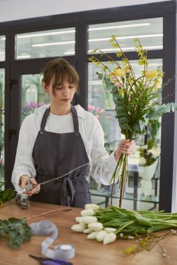 Güzel, genç bir çiçekçi buket yapıyor.