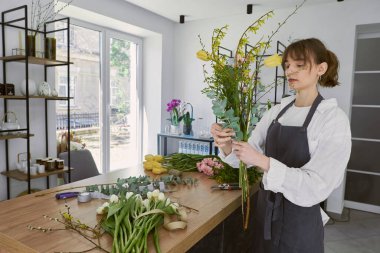 Güzel, genç bir çiçekçi buket yapıyor.