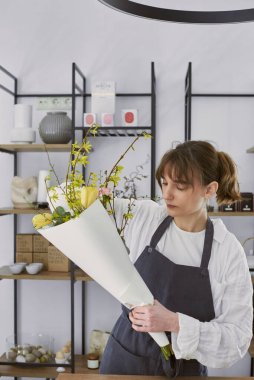 Güzel, genç bir çiçekçi buket yapıyor.