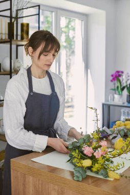 Güzel, genç bir çiçekçi buket yapıyor.
