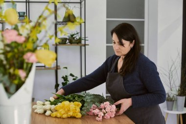 Güzel, genç bir çiçekçi buket yapıyor.