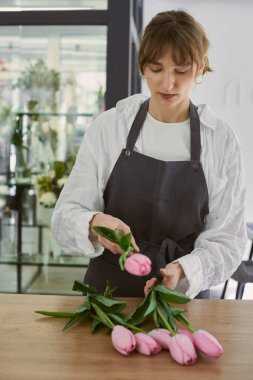 Güzel, genç bir çiçekçi buket yapıyor.