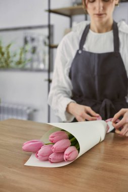 Güzel, genç bir çiçekçi buket yapıyor.