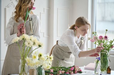 Takım çalışması. İki güzel çiçekçi bir buket oluşturuyor.
