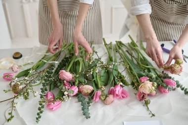 Takım çalışması. İki güzel çiçekçi bir buket oluşturuyor.