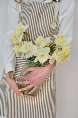 Önlüklü güzel bir çiçekçi ve beyaz arka planda bir buket çiçek.