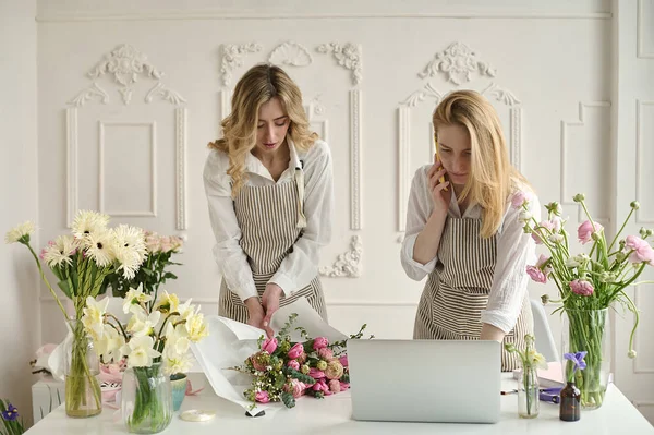 Takım çalışması. İki güzel çiçekçi bir buket oluşturuyor.