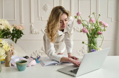 Dizüstü bilgisayar kullanan genç yaratıcı kadın bir çiçek dükkanında. Çiçekçi iş başlangıç.
