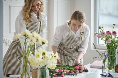 Takım çalışması. İki güzel çiçekçi bir buket oluşturuyor.
