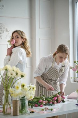 Takım çalışması. İki güzel çiçekçi bir buket oluşturuyor.