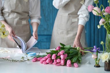 Takım çalışması. İki güzel çiçekçi bir buket oluşturuyor.