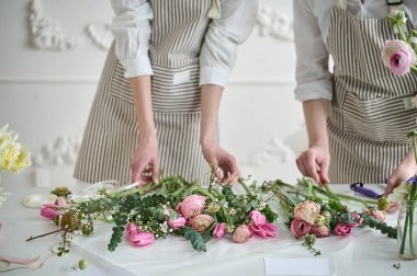 Takım çalışması. İki güzel çiçekçi bir buket oluşturuyor.