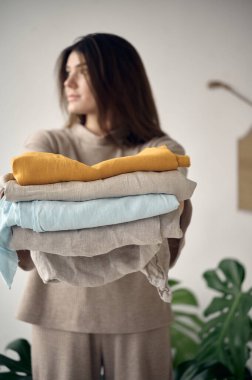 Bir mezura ve ellerinde kumaş yığını olan çekici bir terzi.