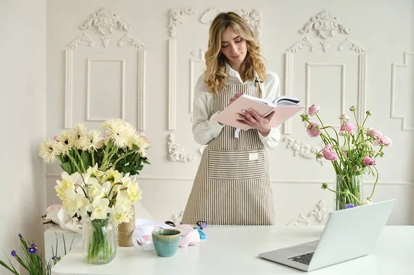 Dizüstü bilgisayar kullanan genç yaratıcı kadın bir çiçek dükkanında. Çiçekçi iş başlangıç.