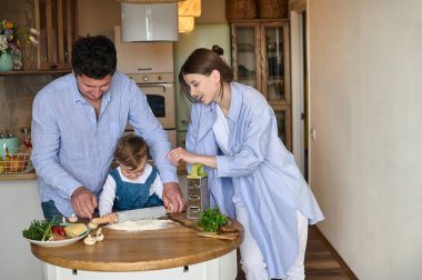 Baba, anne ve kızları mutfakta birlikte pizza pişiriyorlar. Mutlu aile kavramı.