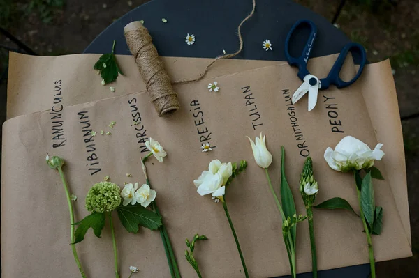 ดอกไม ขาวหลายชน ดวางไว บนกระดาษกระดาษกระดาษบนโต ะในสวน — ภาพถ่ายสต็อก