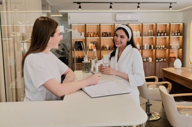 İstemci ile güzellik salonu masasında çalışan genç resepsiyonist