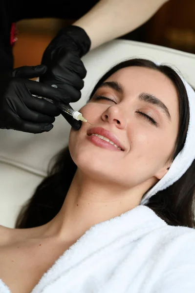 Beauty injection. Woman making correction her nose and lips in salo