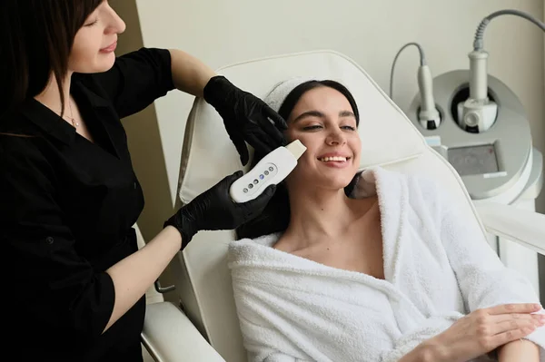 Face peeling mask, spa beauty treatment, skincare. Woman getting facial care by beautician at spa salon