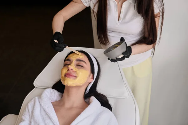 Face peeling mask, spa beauty treatment, skincare. Woman getting facial care by beautician at spa salon