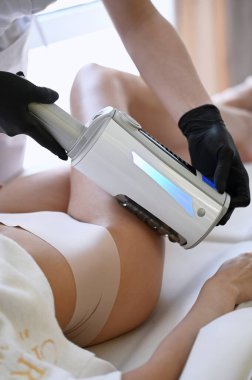 Güzel bir kadın, anti-selülit ve vücut düzeltmesi için son nokta makinesiyle kalça masajından hoşlanır.