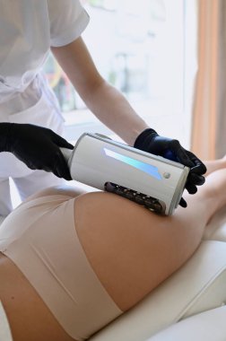 Güzel bir kadın, anti-selülit ve vücut düzeltmesi için son nokta makinesiyle kalça masajından hoşlanır.