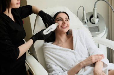 Yüz soyma maskesi, kaplıca güzellik tedavisi, cilt bakımı. Güzellik salonunda güzellik uzmanı bir kadının yüz bakımını alıyor.