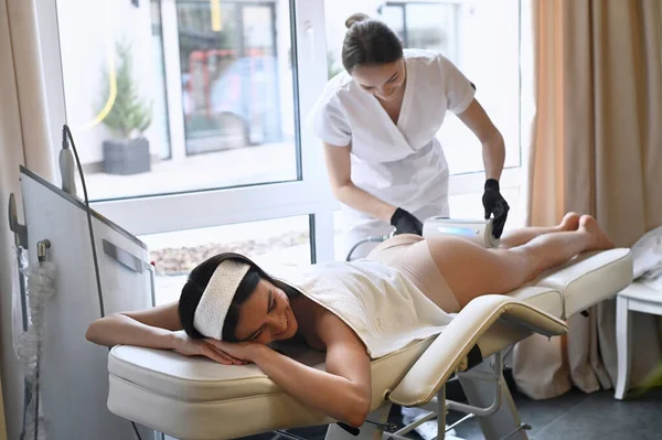 Beautiful woman enjoys buttocks massage with endosphere machine for anti-cellulite and body correction
