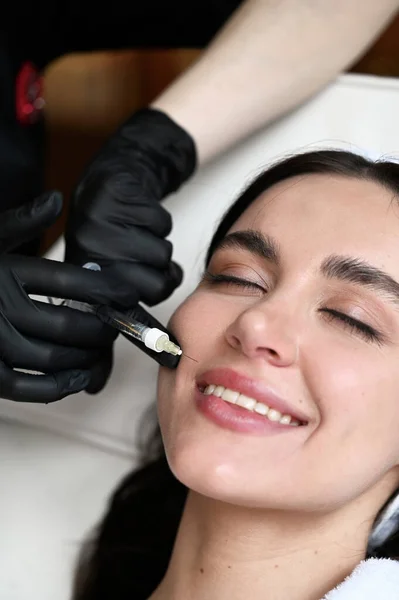 Beauty injection. Woman making correction her nose and lips in salo