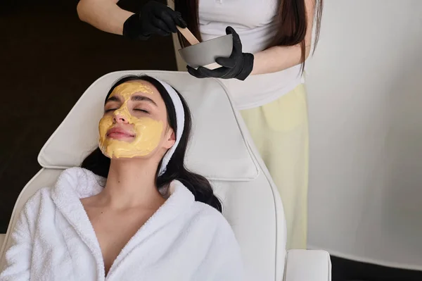 Face peeling mask, spa beauty treatment, skincare. Woman getting facial care by beautician at spa salon