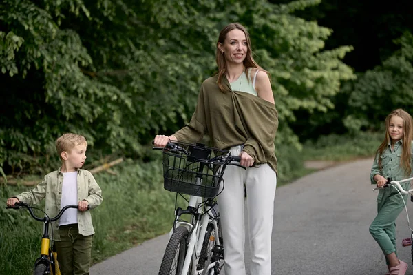 Mom and  her two children cycling in the park. Children summer vacation concept