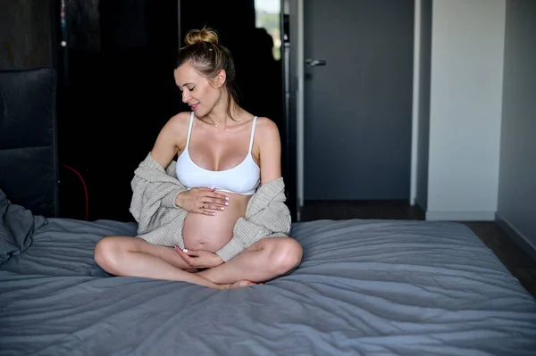 Mutlu Hamile Kadın Yatakta Oturup Karnına Dokunuyor Hamilelik Istirahatı Beklenti — Stok fotoğraf