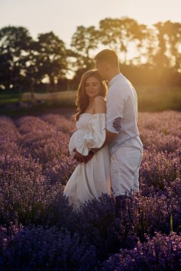 Gün batımında lavanta tarlasında genç ve güzel bir çiftin portresi. Mutlu aile kavramı