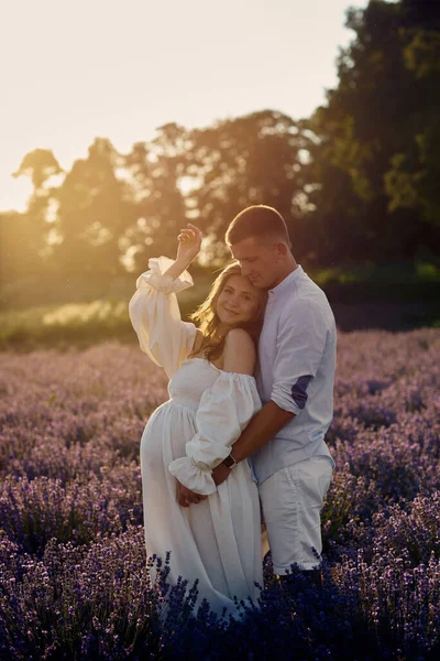 Gün batımında lavanta tarlasında genç ve güzel bir çiftin portresi. Mutlu aile kavramı