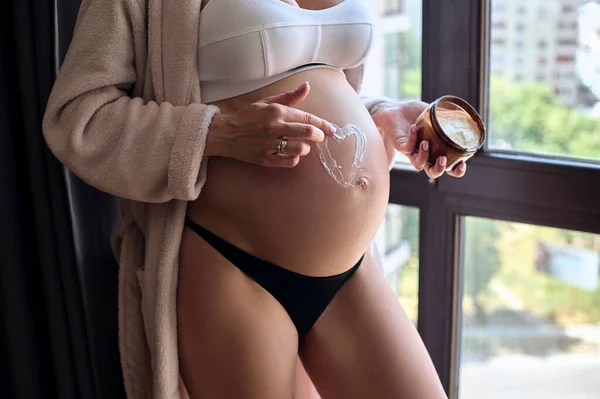 Όμορφη Έγκυος Γυναίκα Μπουρνούζι Απλώνει Μια Κρέμα Στην Κοιλιά Της — Φωτογραφία Αρχείου